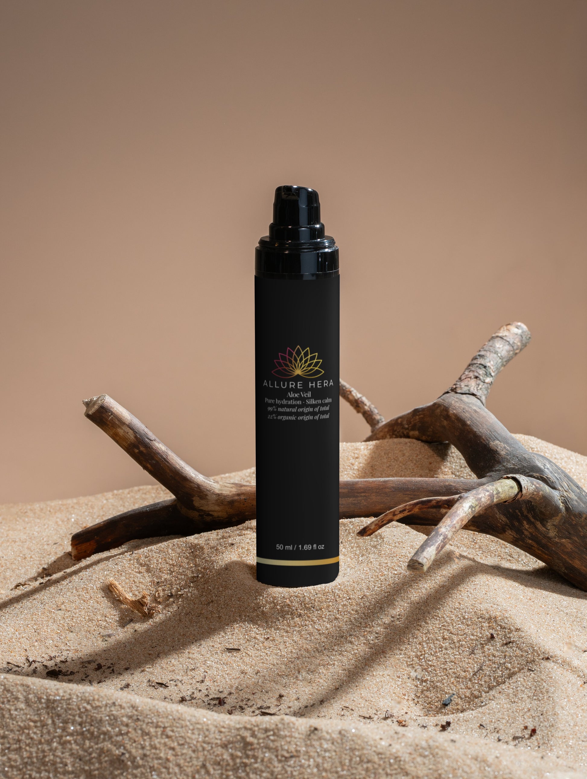 Black spray bottle with brand logo on a sandy surface with driftwood