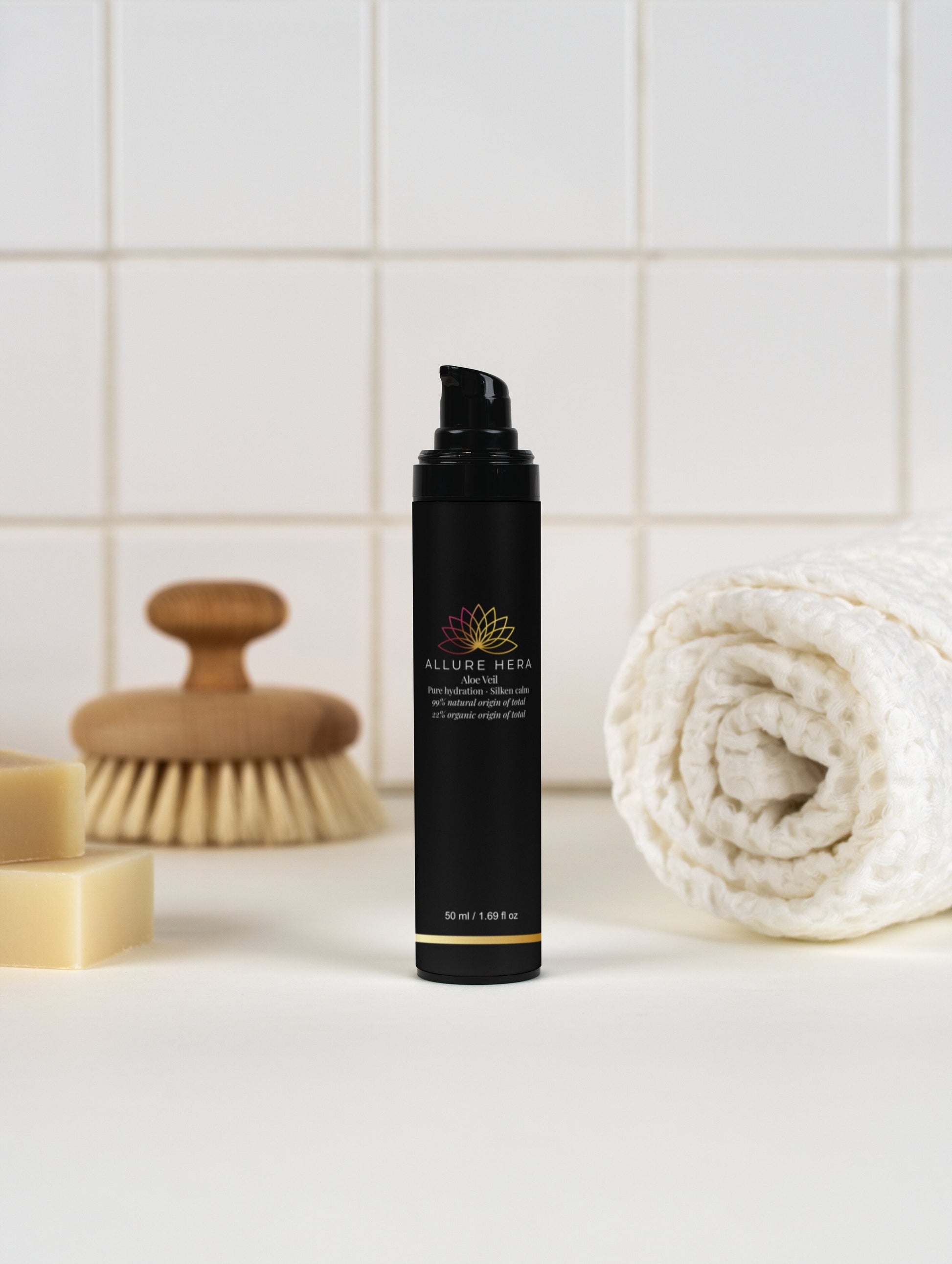 Black bottle with a brand logo on a bathroom counter with a brush, soap, and towel in the background.