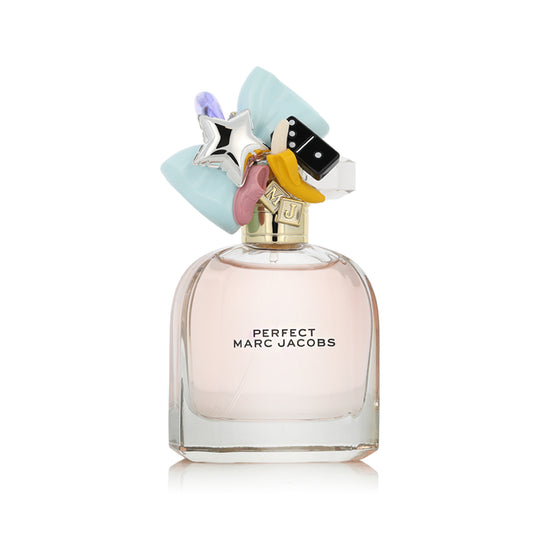 Marc Jacobs Perfect perfume bottle with a light pink liquid, a gold cap, and a whimsical multicolor cap topper featuring a light blue bow, silver star, pink crescent moon, yellow banana, and black-and-white domino piece, on a white background.